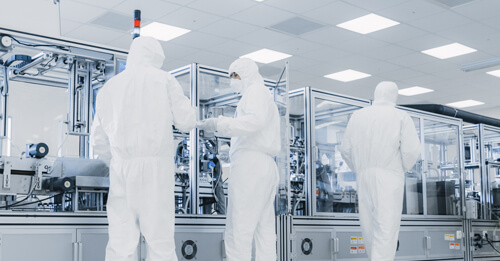 3 technicians in sterile gowning attending to a modular isolator