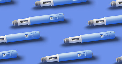 An overhead view of a number of injector pens in blue plastic casing laying down in neat rows