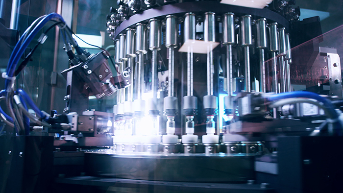 A production line of glass medicine vials with a camera training on them