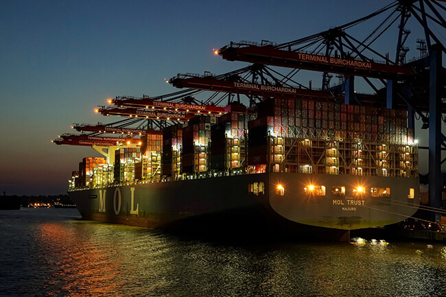 A container ship being loaded in a dock at twilight