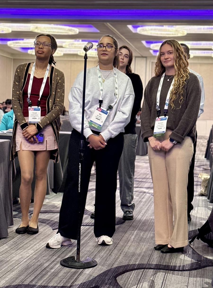 A small group of students stand next to a microphone asking panelists questions