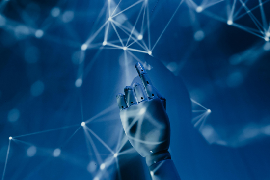 A futuristic robotic hand pointing towards a wall with a lighted projection of connecting lines shining on it and the wall in blue light