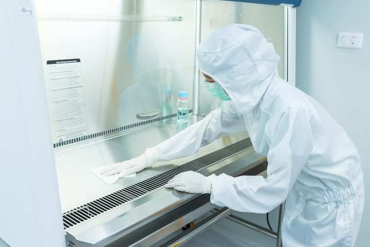 2 workers in sterile gowning working together to clean a table surface